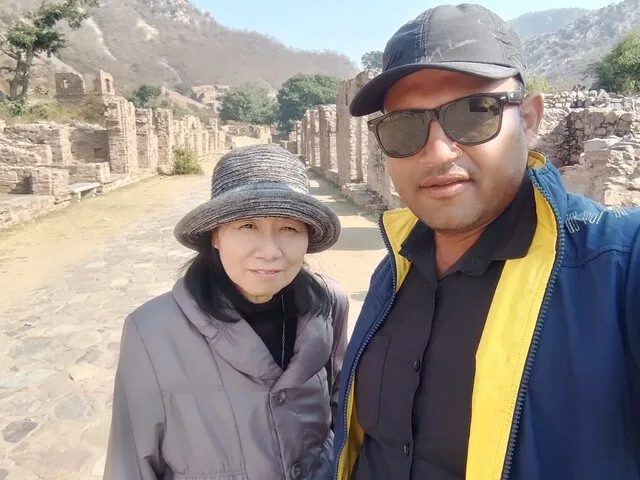 Two people taking a selfie in front of the stone ruins at Bhangarh Fort