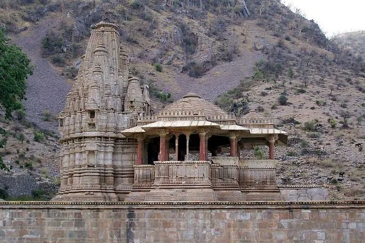 A beautifully carved ancient stone temple situated near a rocky hillside