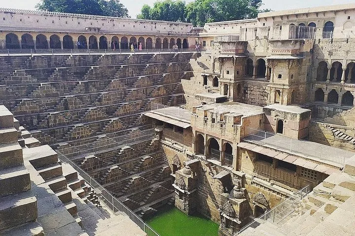 Chand Baori stepwell showing the green water at the bottom and intricate stone stairs